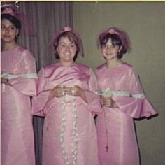 three women in pink dresses are standing together