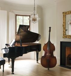 a grand piano sitting next to a black piano in a living room with a chandelier