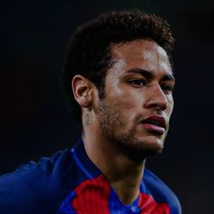 a close up of a soccer player wearing a blue and red uniform with his head turned to the side