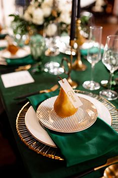 a table set with green and gold place settings