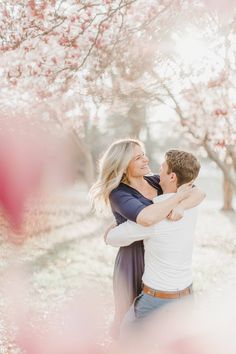 an engaged couple hugging under the blossoming trees