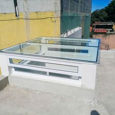 a glass table sitting on top of a cement floor next to a yellow and white building