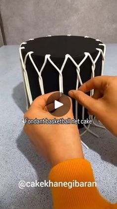 someone is decorating a black and white cake