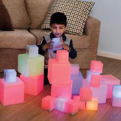 a young boy is playing with glowing blocks on the floor in front of a couch