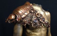 the back of a mannequin's torso is adorned with intricate metal jewelry