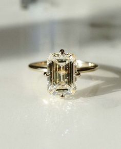 an engagement ring with a green diamond in the center on a white surface, close up