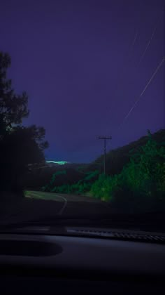 the night sky is lit up with green lights and power lines in the foreground