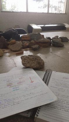 an open notebook sitting on top of a table next to rocks