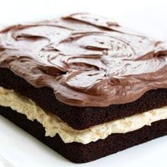 two pieces of cake with chocolate frosting on top sitting on a white plate next to each other