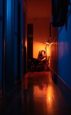 a woman is sitting in a chair at the end of a hallway with blue walls