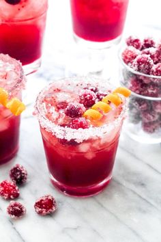 two glasses filled with red drinks and garnished with orange slices