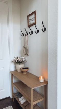 a wooden table sitting in front of a white wall with hooks on the wall above it