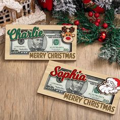 two christmas money signs sitting on top of a wooden table