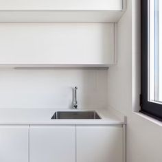 a white kitchen with a sink and window