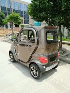 a small car parked on the side of a road next to a tree and building