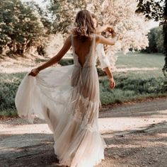 a woman in a dress walking down a dirt road