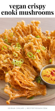 a white plate topped with fried food next to a bowl of dipping sauce and text that reads vegan crispy enoki mushrooms