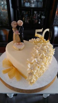 a 50th birthday cake decorated with flowers and a figurine in the shape of a heart