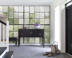 a black and white room with a large glass window behind the console, shoes on the floor