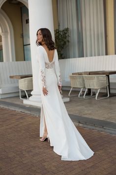 a woman in a white dress is standing outside