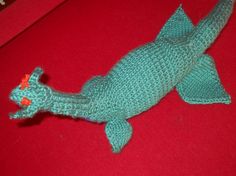 a knitted toy fish laying on top of a red surface