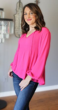 Looking for something pretty, breezy and whimsical? This is the blouse for you! This pink beauty is loose fitting, light weight and fun. The delicate pleated detail is on the front and back and tapers off near the waist. The long sleeves have an elastic cuff and the front is enhanced with the most adorable fringe tie neck. The vibrancy of the pink is nothing short of stunning. Color: Hot Pink Pleated Upper Torso Elastic Cuffs Slightly Longer Back Hem Fringed Neck Tie True to Size Yet Loose Fitti Feminine Long Sleeve Tops With Pleated Sleeves, Pink V-neck Blouse With Blouson Sleeves, Pink Blouson Sleeves V-neck Blouse, Feminine Pink Blouse For Fall, Chic Pink Long Sleeve Top For Spring, Chic Pink Long Sleeve Blouse, Chic Long Sleeve Pink Blouse, Trendy Pleated Spring Tops, Trendy Pleated Tops For Spring