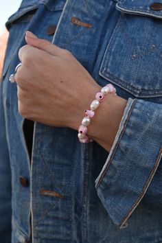 This enchanting white and pink Mother of Pearl and pink Evil Eye beaded bracelet seamlessly blends classic elegance with spiritual symbolism. The soft pink hues of the Mother of Pearl beads add a delicate touch of femininity, making this bracelet a versatile accessory that can be dressed up or down to suit any occasion. The pink Evil Eyes and a touch of mystique, making it a perfect accessory for anyone who loves spiritual and mystical symbolism. The Evil Eye is a symbol of protection, warding o Pink Beaded Rosary Bracelet, Pink Beaded Rosary Bracelet With Round Beads, Adjustable Pink Rosary Bracelet With 8mm Beads, Pink Beaded Pearl Bracelet, Pink Beaded Pearl Bracelet With Round Beads, Adjustable Handmade Pink Rosary Bracelet, Adjustable Pink Rosary Bracelet With Colorful Beads, Adjustable Pink Beaded Bracelets With 8mm Beads, Handmade Pink Spiritual Beaded Bracelets