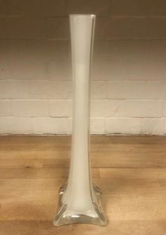 a tall white vase sitting on top of a wooden floor