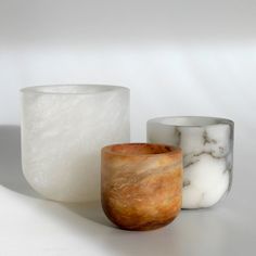 three glass vases sitting on top of a white table