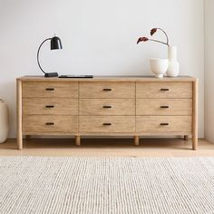 a wooden dresser with two vases on top and a rug in front of it