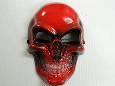 a red plastic skull mask hanging on a white wall in front of a white background