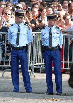 two police officers standing next to each other in front of a large group of people