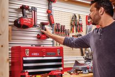 a man working on a tool rack in a garage with tools hanging on the wall