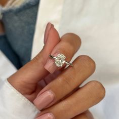 a woman's hand holding a ring with a diamond on it and the middle finger