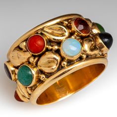 This multi-gemstone wide band ring features a nugget design and is bezel set with one (1) natural aventurine, one (1) natural carnelian, one (1) natural crystal opal, one (1) natural citrine, one (1) natural tiger's eye quartz, two (2) natural rhodolite garnet, one (1) natural amethyst, one (1) natural black onyx and two (2) natural nephrite jade. The band measures 14.1mm wide and 2.8mm thick and has a great patina. It is a size 7.5 and we are not offering resizing due to the design of the ring. The carnelian is lightly chipped but this not visible without magnification. Gold Drop Necklace, Pretty Accessories, Peridot Jewelry, Wide Band Ring, Nephrite Jade, How To Make Rings, Crystal Opal, Citrine Ring, Wide Band Rings