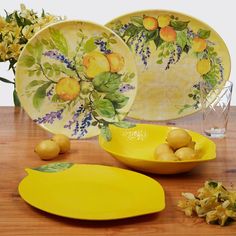 yellow plates and bowls on a wooden table with flowers in vases next to them