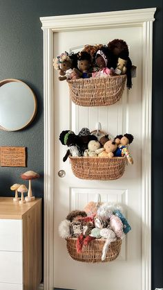 two baskets filled with stuffed animals hanging on the wall next to a white front door