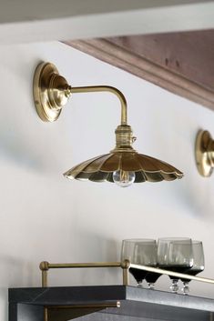 two wine glasses sitting on top of a shelf next to a light fixture in a room