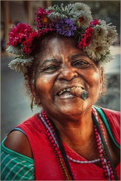 a woman with flowers in her hair and piercings on her nose is smiling at the camera