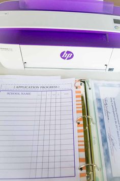 a binder sitting on top of a desk next to a printer and paper pad