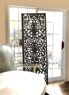 a room divider in front of a window with an ornate design on the screen