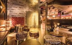 the interior of a restaurant with leopard print chairs and stools in front of a stone wall