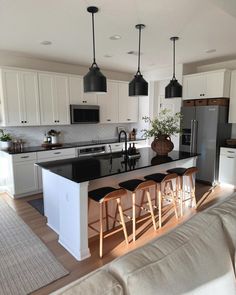 a kitchen with an island and stools in the center, surrounded by white cabinets