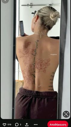 the back of a woman's body with flowers on it, in front of a mirror