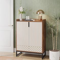 a white and brown cabinet sitting next to a potted plant