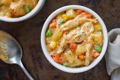 two bowls filled with pasta and vegetables on top of a table next to a spoon