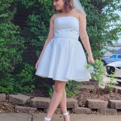 a woman in a white dress is walking down the street