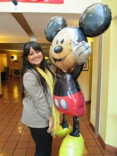 a woman standing next to a mickey mouse balloon