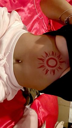 a woman with a sun tattoo on her stomach is laying down and looking at the camera