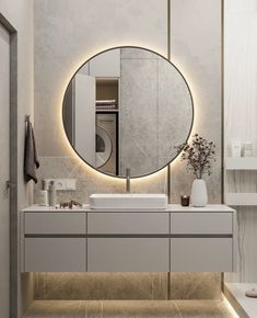 a bathroom with a large round mirror above the sink and a washer dryer